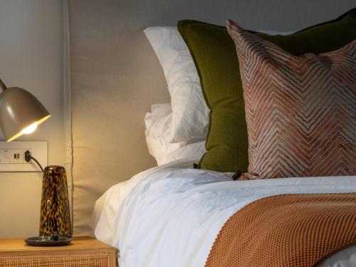 a bed with green and white pillows and a lamp at Nomads Den Safari Villas - Heated Pools and Riverbed views in Hoedspruit