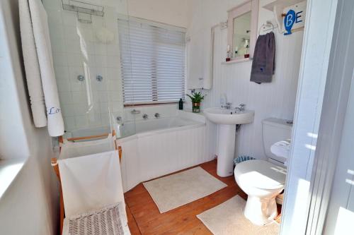 uma casa de banho com uma banheira, um WC e um lavatório. em Kykmar Beach House em Stilbaai