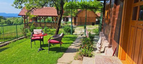 a patio with two chairs and a table on the grass at Kokotova hiža in Gornja Konjšćina