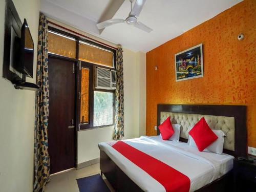 um quarto com uma cama com almofadas vermelhas e uma televisão em HOTEL JKM PALACE Near Apollo Hospital em Nova Deli