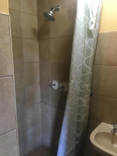 a shower with a shower curtain next to a sink at Kwa-Crossing 