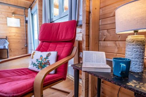 a red chair sitting next to a table with a laptop at The Cabin, Parham in Woodbridge