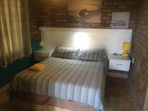 Schlafzimmer mit einem Bett mit gestreifter Decke in der Unterkunft Kwa-Crossing 