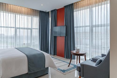 um quarto com uma cama, uma cadeira e janelas em Salalah International Hotel em Salalah