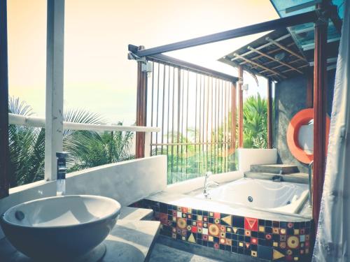 a bathroom with a tub and a sink and a window at Vartika Resovilla Kuiburi Beach Resort and Villas in Kui Buri