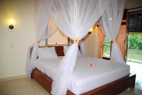 a bedroom with a bed with white drapes at Tiara Homestay Pemuteran Bali in Pemuteran