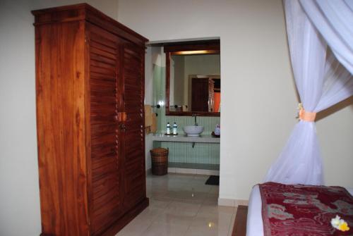 Tiara Homestay Pemuteran Bali في بيموتيران: حمام فيه باب خشبي كبير ومغسلة