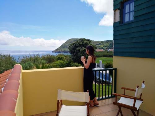 Una donna in piedi su un balcone che guarda l'oceano di Varandas Miramar ad Angra do Heroísmo