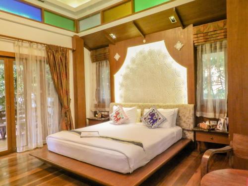 a bedroom with a white bed in a room with windows at Vartika Resovilla Kuiburi Beach Resort and Villas in Kui Buri