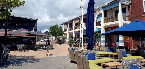a man standing on a street with chairs and umbrellas at Ti jacques location - Saint-Gilles les bains - studio pour 2 personnes in Saint-Paul