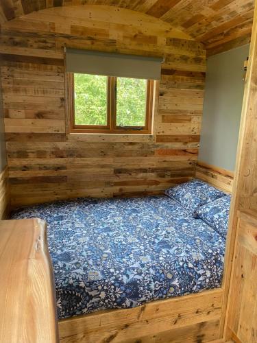 a bed in a log cabin with a window at The Hive Shepherds hut in Offton