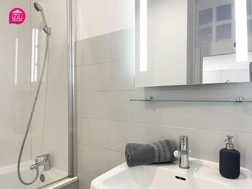 La salle de bains blanche est pourvue d'un lavabo et d'une douche. dans l'établissement Le Grand'rue by iZiLi - Centre Ville - Confort, à Poitiers