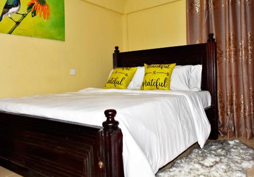 1 cama con sábanas blancas y almohadas amarillas en one bedroom in oj town ruiru, en Kiambu
