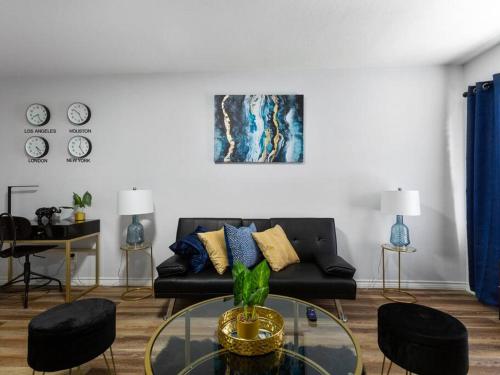 a living room with a black couch and a glass table at Golden Vibes Dwtn,Eado,Nrg,MedCtr,MTR,Rodeo in Houston