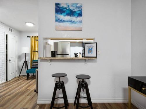 a living room with two stools and a mirror at Golden Vibes Dwtn,Eado,Nrg,MedCtr,MTR,Rodeo in Houston