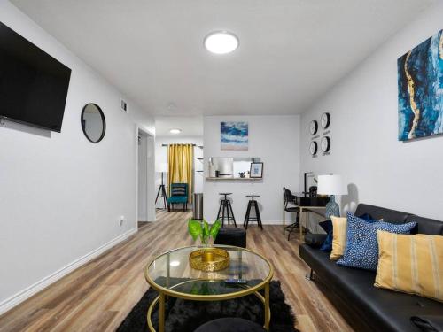 a living room with a black couch and a glass table at Golden Vibes Dwtn,Eado,Nrg,MedCtr,MTR,Rodeo in Houston
