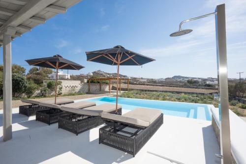 a patio with a table and umbrellas and a swimming pool at Private Villa Màou in Ano Mera
