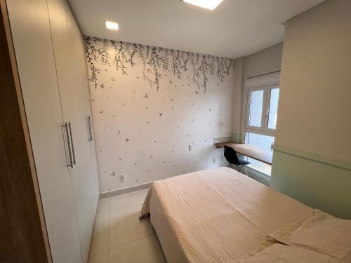 ein Schlafzimmer mit einem Bett und einer Wand mit Blumen in der Unterkunft Apartamento no Jardim Goiás em Goiânia in Goiânia