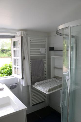 une salle de bain blanche avec une douche et un lavabo dans l'établissement Longère de charme à 3 kilomètres de la mer, à Bénodet