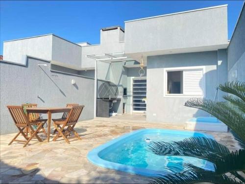 a patio with a table and chairs and a swimming pool at Casa com piscina duas quadras da praia in Guaratuba