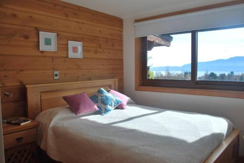 um quarto com uma cama grande e uma janela em Preciosa casa, vistas y piscina privada em Pucón