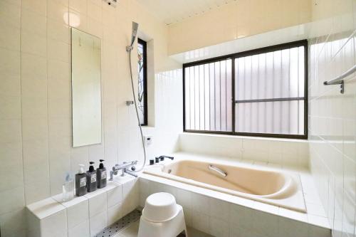 a bathroom with a tub and a sink and a window at Samp,Inn - Vacation STAY 27372v in Fukuoka