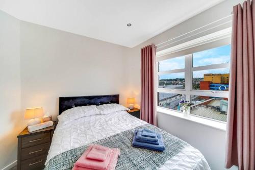 um quarto com uma cama e uma grande janela em The Peace Bridge Apartment em Derry