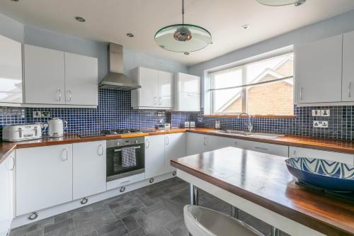 cocina con armarios blancos y mesa de madera en 2 bedr apmt, seaview terrace, central Broadstairs, en Broadstairs