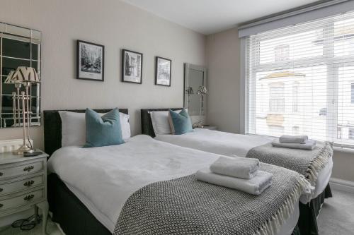um quarto com 2 camas com almofadas azuis em 2 bedr apmt, seaview terrace, central Broadstairs em Broadstairs
