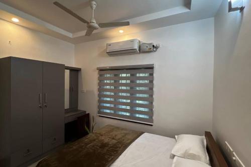 a bedroom with a bed and a window with a air conditioner at Hosted by Resmi Jayalal in Cochin