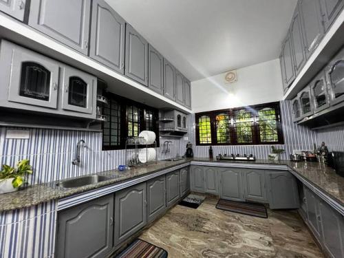 a large kitchen with gray cabinets and a sink at Hosted by Resmi Jayalal in Cochin