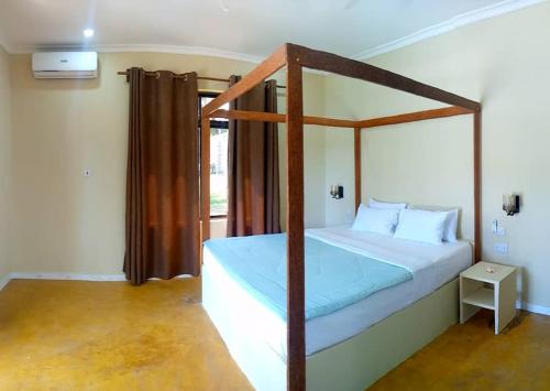 ein Schlafzimmer mit einem Bett mit einem Bettrahmen aus Holz in der Unterkunft Mafia Neptune Villa Lodge in Utende