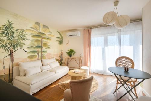 een woonkamer met een witte bank en een tafel bij Appartement Mérignac Mondésir in Mérignac