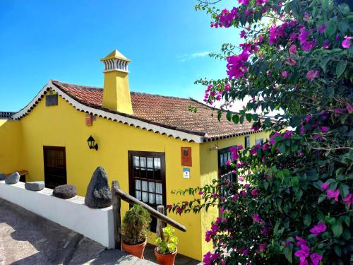 una casa amarilla con chimenea y flores en Dos Aguas, en Mazo