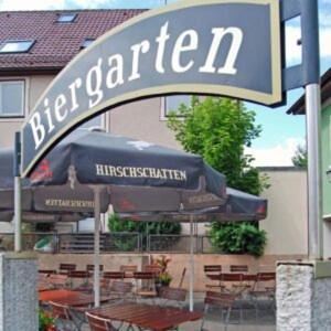 a sign for a restaurant with chairs and an umbrella at Landgasthof Kreuz mit Gästehaus in Immendingen