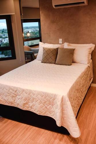 a bedroom with a large bed with white sheets and pillows at Loft com vista para o Parque Una in Pelotas