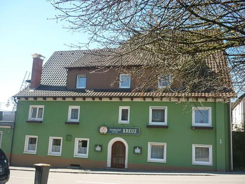 un bâtiment vert avec une horloge à l'avant dans l'établissement Landgasthof Kreuz mit Gästehaus, à Immendingen