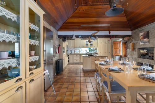 una cocina con techos de madera y una mesa con sillas. en Quinta do Carvalhal Casa Privada, Penafiel, en Irivo