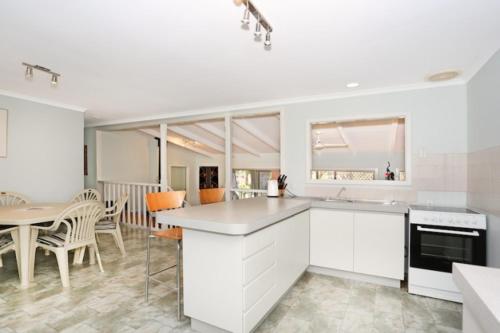 a kitchen with white cabinets and a table and chairs at Amazing River House in North Yunderup