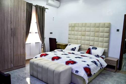 - une chambre avec un grand lit blanc et des oreillers rouges dans l'établissement HKB APARTMENTS, à Ibadan