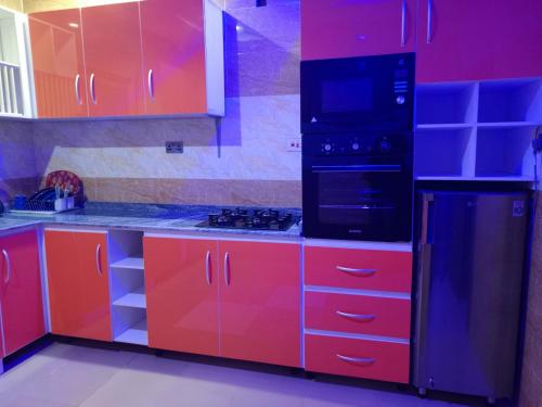 une cuisine avec des armoires rouges et un appareil noir dans l'établissement HKB APARTMENTS, à Ibadan