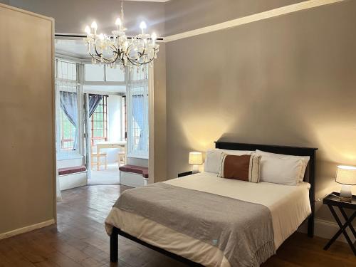 - une chambre avec un lit et un lustre dans l'établissement Lindela House, à Kokstad