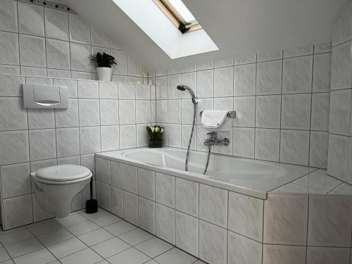 a bathroom with a bath tub and a toilet at Hotel Schnepper in Attendorn