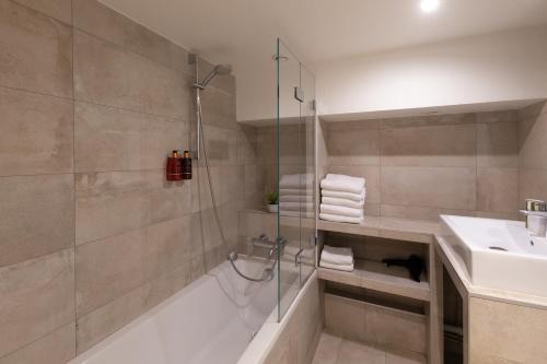 y baño con ducha, bañera y lavamanos. en Edgar Suites Louvre - Richelieu 2 en París
