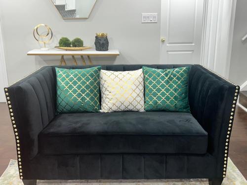 a black leather couch with two pillows on it at Tosam Luxury Lodge Two Bedroom Suite in Brampton