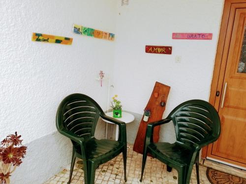 twee groene stoelen in een kamer met een tafel bij Casa dos Quatro Irmãos in Gouveia