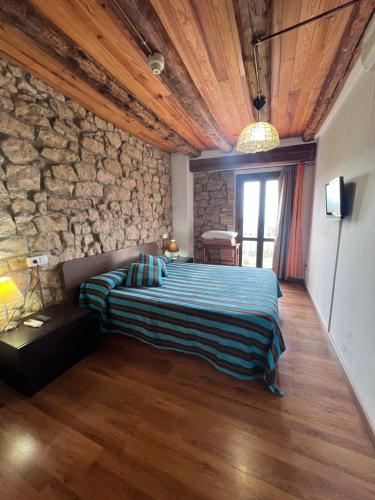 um quarto com uma cama e uma parede de pedra em La Garbinada Hotel em Grañena de las Garrigas
