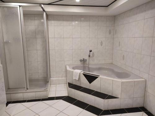 a white bathroom with a tub and a shower at Gästewohnung Mühlstein in Hohenthann