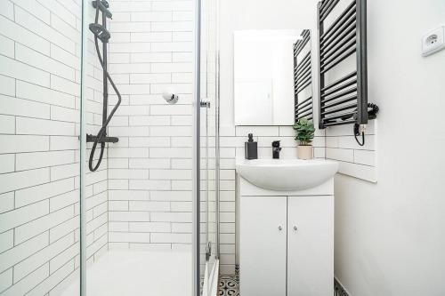 a white bathroom with a sink and a shower at Cozy apartment in hipster area in Prague