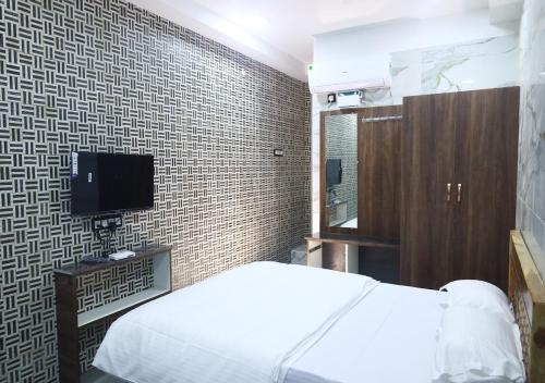 ティルヴァンナーマライにあるAnanda Residencyのベッドルーム(白いベッド1台、テレビ付)
